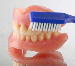 Photo: Nettoyage d'une prothèse amovible avec une brosse à dents conventionnelle