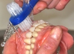 Photo: Nettoyage d'une prothèse amovible avec une brosse spéciale